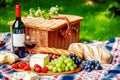 Bottle of red wine, baguete, cheese, grapes and fresh fruits on plaid on blurred landscape Royalty Free Stock Photo