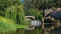 Beautiful summer scene on Este river in Portugal with Roman stone bridge, waterfall and overhanging willow tree.