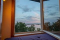 Beautiful summer sundown view from open window. Top of green trees on lake and cloudy sky background Royalty Free Stock Photo