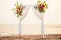 Beautiful summer wedding ceremony outdoors. Wedding arch made of light cloth and white and pink flowers on sea at sunset Royalty Free Stock Photo