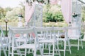 Beautiful summer wedding ceremony outdoors. Decorated chairs stand on the grass. Wedding arch made of light cloth and white and pi Royalty Free Stock Photo