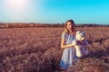 Beautiful summer woman wheat field, blue dress, hands of children`s toy teddy bear. Free space for text. Rest rural Royalty Free Stock Photo