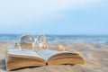 Beautiful sunglasses, book and shell on sand near sea, space for text