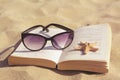 Beautiful sunglasses, book and starfish on sand, closeup Royalty Free Stock Photo