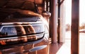 Beautiful sunlight. Front part of brand new modern car. Parked at showroom. Reflection in the headlights Royalty Free Stock Photo