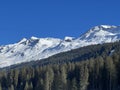 Beautiful sunlit and snow-capped alpine peaks above the tourist sports-recreational winter resorts of Valbella and Lenzerheide Royalty Free Stock Photo