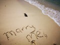 Marry Me written on sandy beach and beautiful sunny day with blue sky Royalty Free Stock Photo