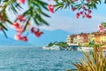 Beautiful sunny summer view of Bellagio town at lake Como in Italy with blooming nerium oleander flowers, ships and Royalty Free Stock Photo