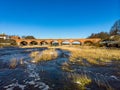 Beautiful sunny view of river wenta flowing towards old brick bridge in old historic countryside city Kuldiga Royalty Free Stock Photo