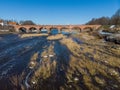 Beautiful sunny view of river wenta flowing towards old brick bridge in old historic countryside city Kuldiga Royalty Free Stock Photo