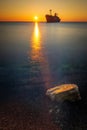 Beautiful sunrise on a beach at sea with a ship wreck in the background