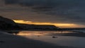 Beautiful sunrise landscape image of Kennack Sands in Cornwall UK wuth dramatic moody clouds and vibrant sunburst