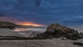 Beautiful sunrise landscape image of Kennack Sands in Cornwall UK wuth dramatic moody clouds and vibrant sunburst