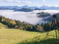 Photo of camera on a tripod taking photos of beautiful sunrise landscape of Saint Thomas Church in Slovenia on hilltop