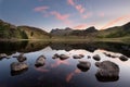 Perfect reflections of a beautiful sunrise with scattered rocks in foreground at Blea Tarn in the Lake District, UK. Royalty Free Stock Photo