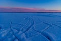 A beautiful sunrise scenery with frozen lake and tracks in the snow.