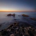 Beautiful sunrise at sea shore and wet rocks in water. soft light, pink sky. Square landscape. nature Royalty Free Stock Photo