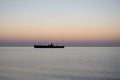 Beautiful sunrise at sea. The silhouette of an abandoned wreck in the sea