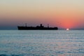 Beautiful sunrise at sea. The silhouette of an abandoned wreck in the sea