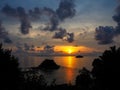 Beautiful sunrise sea view with small island and dark cloud through green tree leaves silhouette, Lipe island, Thailand Royalty Free Stock Photo