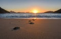 Beautiful sunrise, solar path on water and footprints at the deserted Praia Vermelha Beach