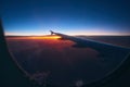 Beautiful sunrise view through the porthole during the flight. Plane wing above the cloudy colorful sunset Royalty Free Stock Photo