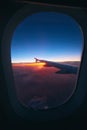 Beautiful sunrise view through the porthole during the flight. Plane wing above the cloudy colorful sunset Royalty Free Stock Photo