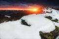 Beautiful sunrise in the winter mountains. View of snow covered stones and dramatic clouds at the distance. Royalty Free Stock Photo