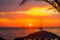 Beautiful sunset above sea. Palm tree and bungalow roof. Photo Wallpaper Royalty Free Stock Photo