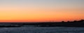 Beautiful sunset on beach in Portugal, with rocks, beach huts and lifebuoys in silhouette