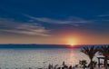 Beautiful sunset at Dead Sea coastline in Jordan. Tropical beach with palm trees and desert plan Royalty Free Stock Photo