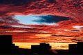 Beautiful sunset with fallstreak hole in red fiery sky and a buildings silhouette