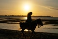 Beautiful sunset at Gili Tranwagan beach. Unrecognizable young woman photographed on a horse during a walk on the beach. Royalty Free Stock Photo