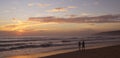 Beautiful sunset on Karon beach. The surf pounds the shore. Dark dim silhouettes of a man and a woman walking arm in arm along sur Royalty Free Stock Photo