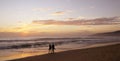 Beautiful sunset on Karon beach. The surf pounds the shore. Dark dim silhouettes of a man and a woman walking arm in arm along sur Royalty Free Stock Photo