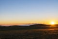 Beautiful sunset landscape. The green field and mountains illuminates the sun rays.