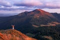 Beautiful sunset. Landscape of the mountains. On the lawn in the bushes of blueberries girl stays with the back pack. Silhouette.