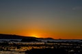 Beautiful sunset over a bay with the sun hiding behind the mountain and tree Royalty Free Stock Photo