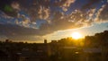 Beautiful sunset over cityscape with gray fluffy clouds and golden sun in blue sky. Royalty Free Stock Photo