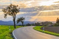 Beautiful sunset over countryside landscape of rolling hills with sun beams piercing sky and lighting hillside Royalty Free Stock Photo