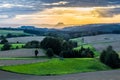 Beautiful sunset over countryside landscape of rolling hills with sun beams piercing sky and lighting hillside Royalty Free Stock Photo