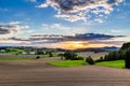 Beautiful sunset over countryside landscape of rolling hills with sun beams piercing sky and lighting hillside Royalty Free Stock Photo