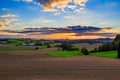 Beautiful sunset over countryside landscape of rolling hills with sun beams piercing sky and lighting hillside Royalty Free Stock Photo