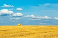 Beautiful sunset over farm field with many hay bales with blue sky and colorful clouds in background