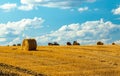 Beautiful sunset over farm field with many hay bales with blue sky and colorful clouds in background