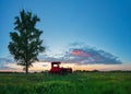 Beautiful sunset over field and old rusty tractor Royalty Free Stock Photo