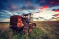 Beautiful sunset over field and old rusty tractor Royalty Free Stock Photo