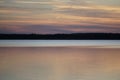 Beautiful sunset over the forest lake. Sun, calm quiet waves a nd reflection Royalty Free Stock Photo