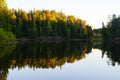 Beautiful sunset over the Karelian forest on shore of Lake Ladoga. The sun painted the tops of the pines yellow. Reflection of Royalty Free Stock Photo