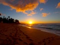 Beautiful Sunset over the ocean and beach with waves moving to shore and foot prints in the sand Royalty Free Stock Photo